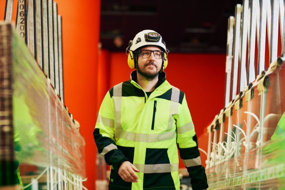 Suojavarusteisiin pukeutunut työntekijä kävelemässä teollisessa ympäristössä