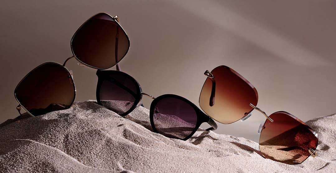 Solglasögon ligger på en sandbädd