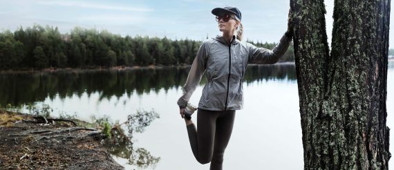 Kvinde med løbebriller strækker ud foran en sø
