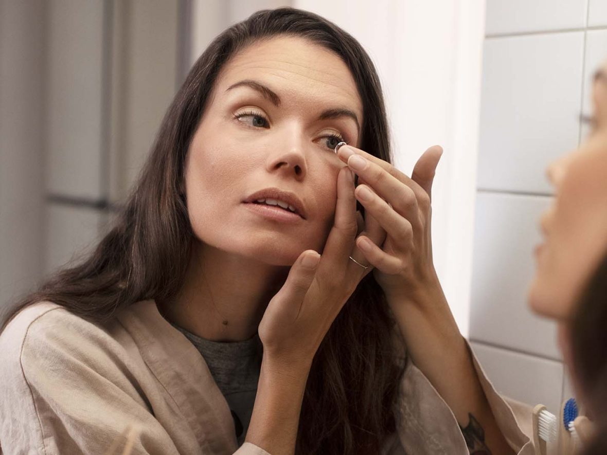 Kvinde tager kontaktlinser i foran spejl