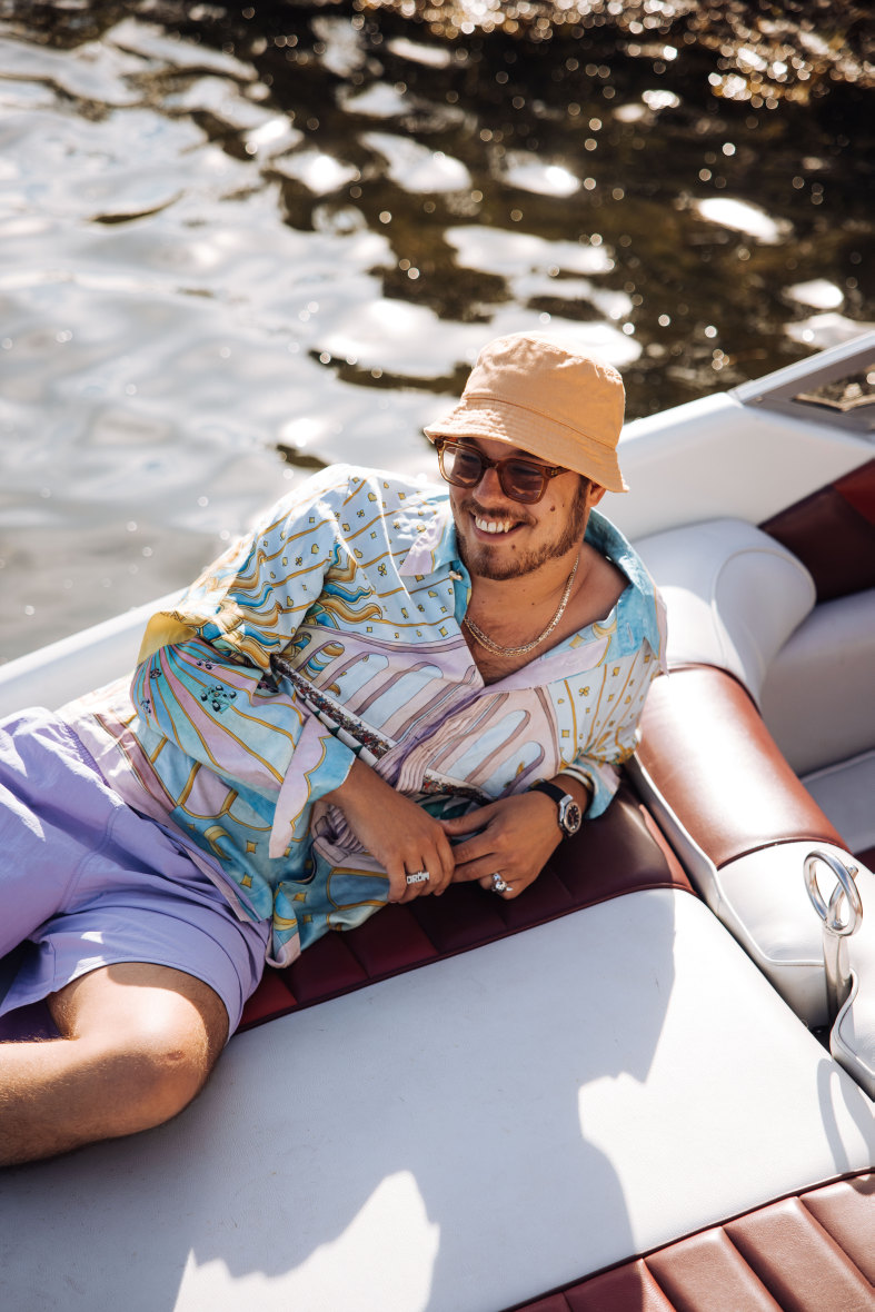 En mann med solbriller ligger på båten i solen