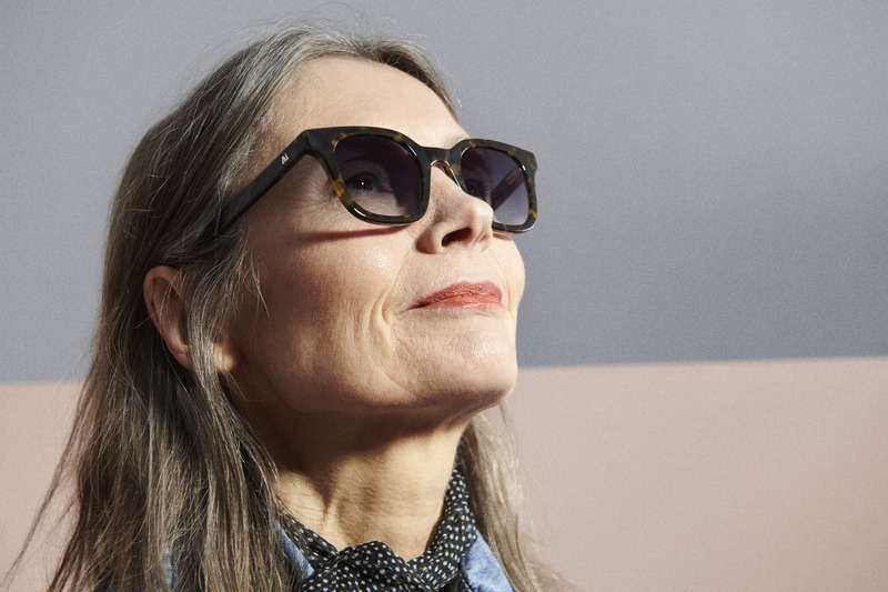 Seniorkvinna som har solglasögon och tittar upp